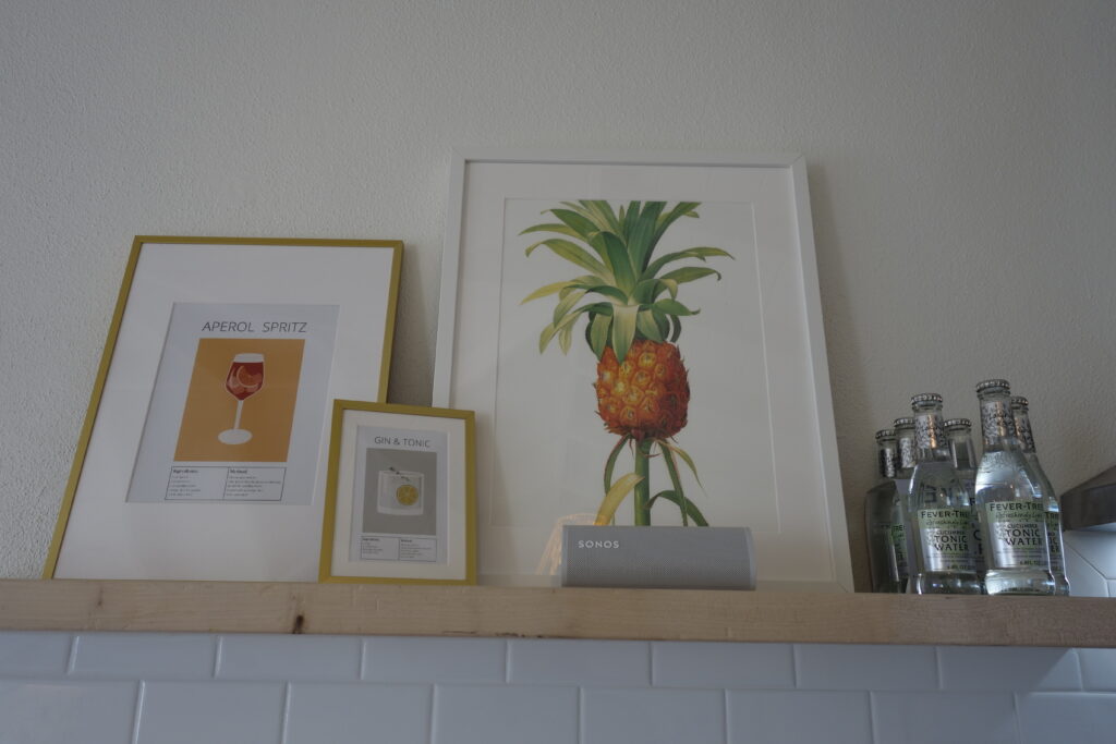 Framed drinks recipe and fruits on a shelf in the kitchen of Sunrise Turtle rental beach cabana