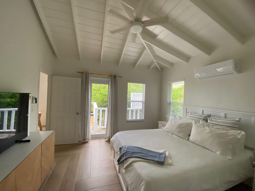 Queen bed and smart TV with view from master bedroom of Sunrise Turtle rental beach villa at Four Turtles Villas